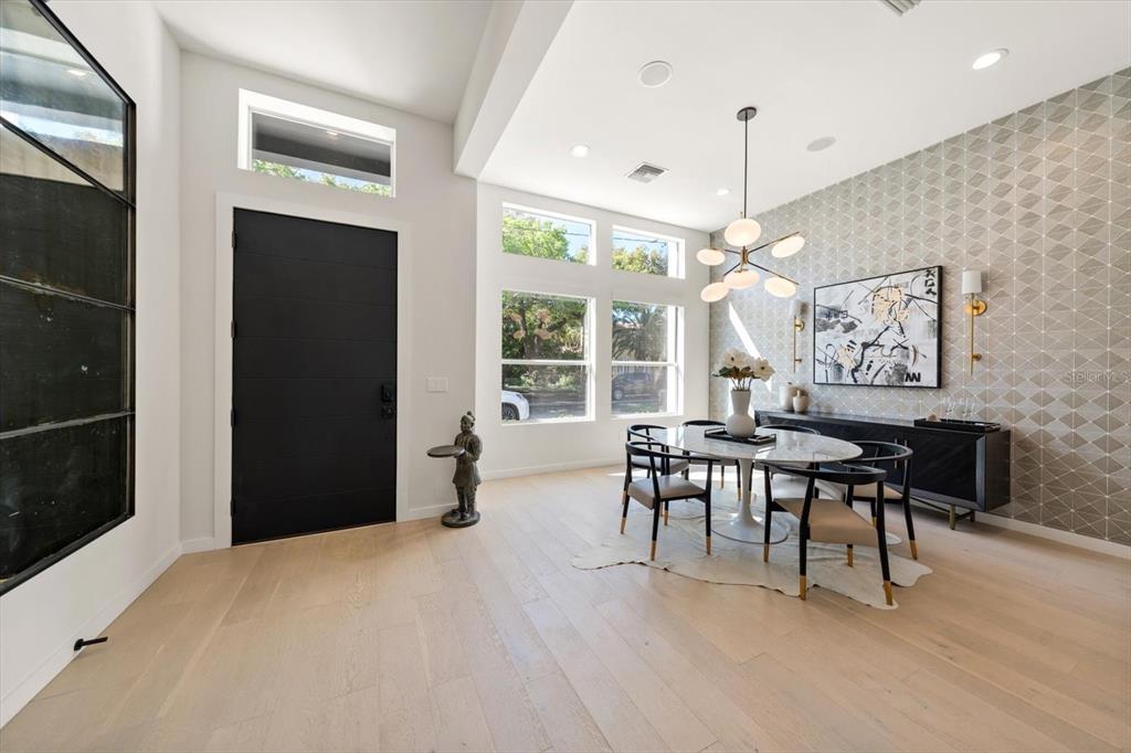 A dining room features light wood floors, a patterned accent wall, and a modern chandelier — 3901 W GRANADA STREET, TAMPA, FL