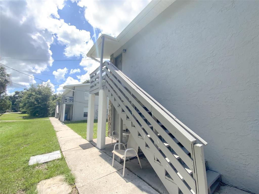 An exterior view of a building with a wooden staircase leading to an upper unit — 2205 IRENE STREET UNIT 3, LUTZ, FL