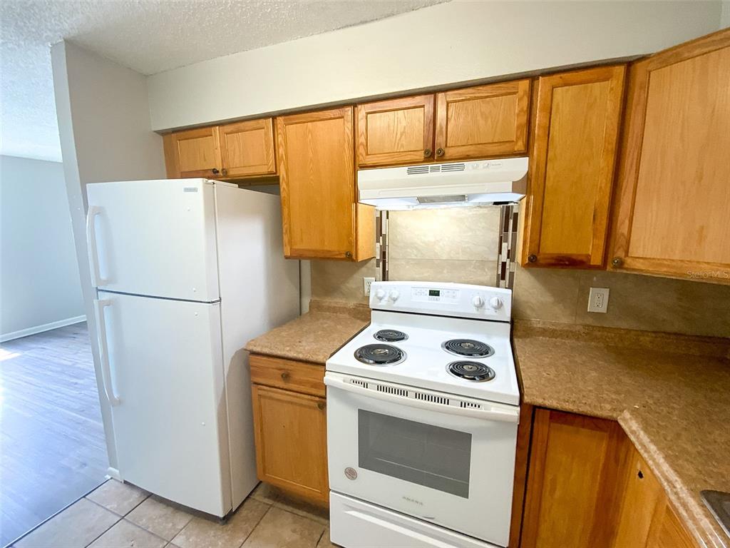 A kitchen features light wood cabinets, white appliances, and a tan laminate countertop — 2205 IRENE STREET UNIT 3, LUTZ, FL