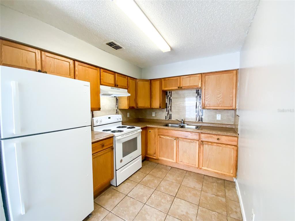 A kitchen features light wood cabinets, white appliances, tile flooring, and a tiled backsplash — 2205 IRENE STREET UNIT 3, LUTZ, FL