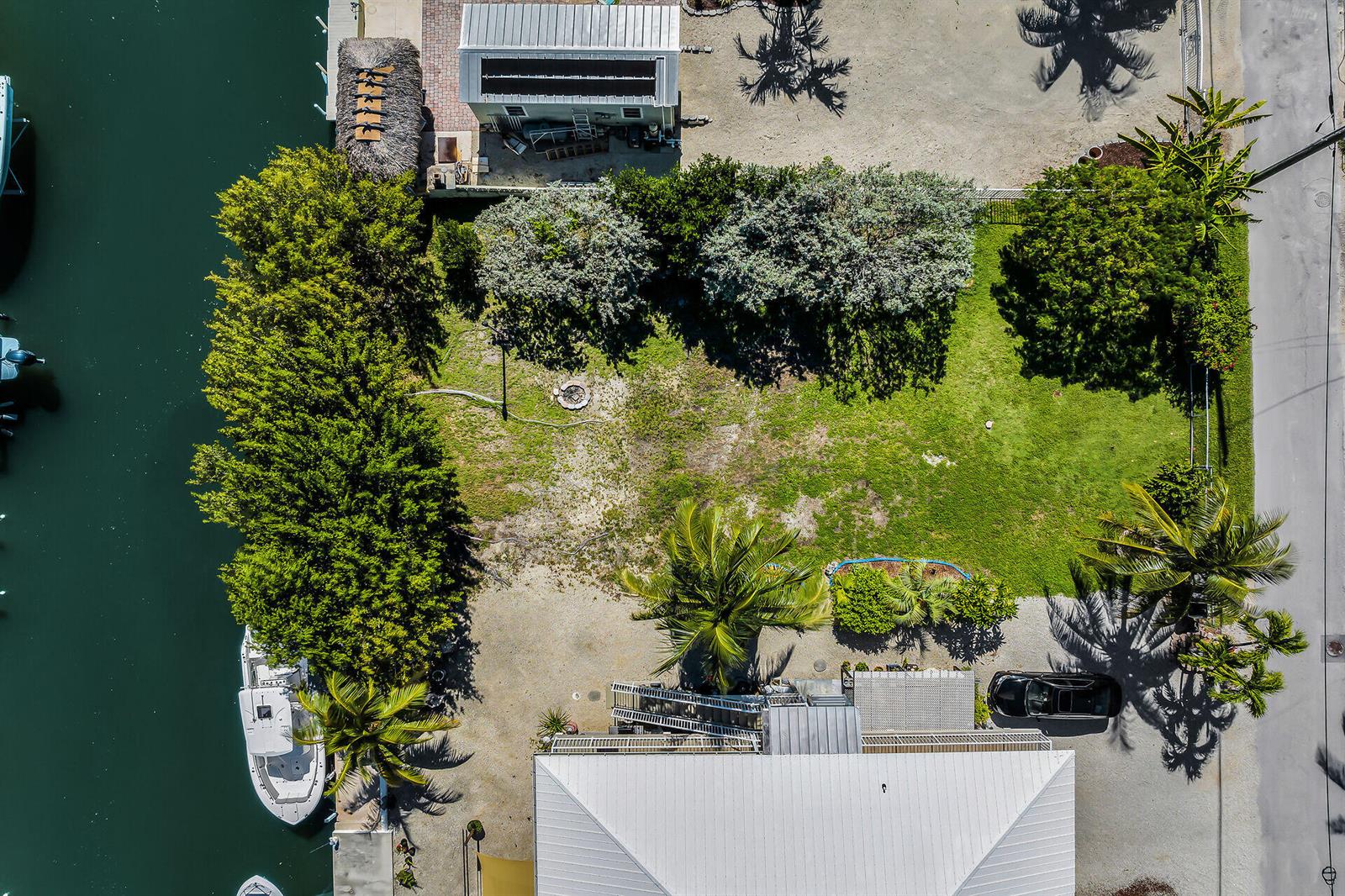 An aerial view shows a waterfront property with a house, boat, and grassy yard — 149 Iroquois Drive, Islamorada FL 33036, ISLAMORADA, FL
