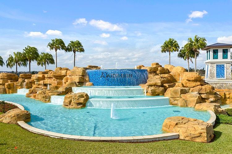 A tiered stone waterfall fountain with blue tile accents sits in front of palm trees — 12014 SHINE VIEW LANE, WINTER GARDEN, FL