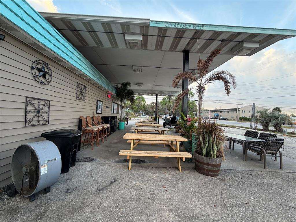 An outdoor covered patio area features wooden picnic tables, bar stools, and potted plants — 1095 US HIGHWAY 17 S, BARTOW, FL