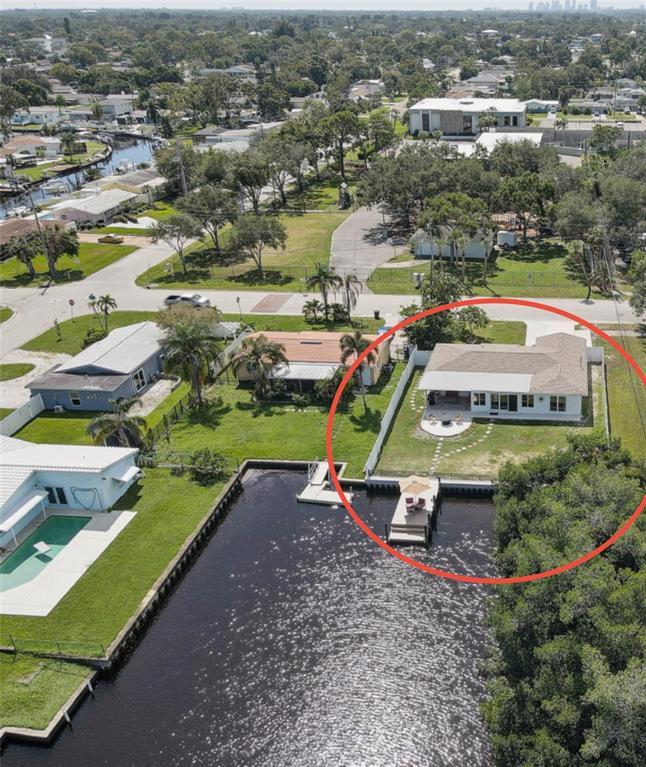 An aerial view shows a waterfront house with a backyard patio and a private dock — 265 96TH AVENUE N, ST PETERSBURG, FL