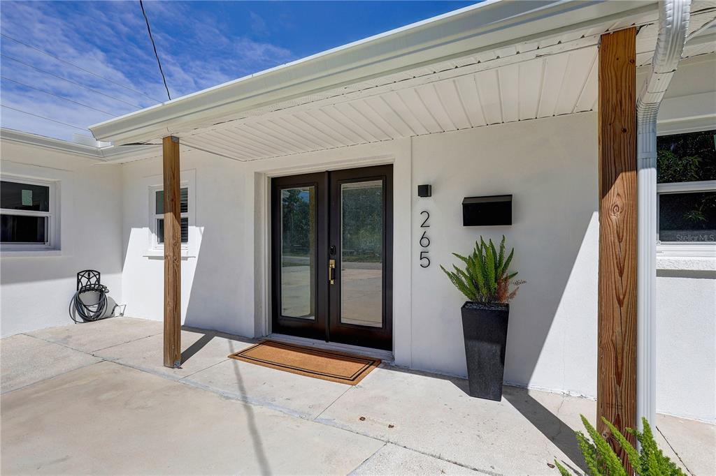 The exterior of a white house features a double glass door entrance and wooden posts — 265 96TH AVENUE N, ST PETERSBURG, FL