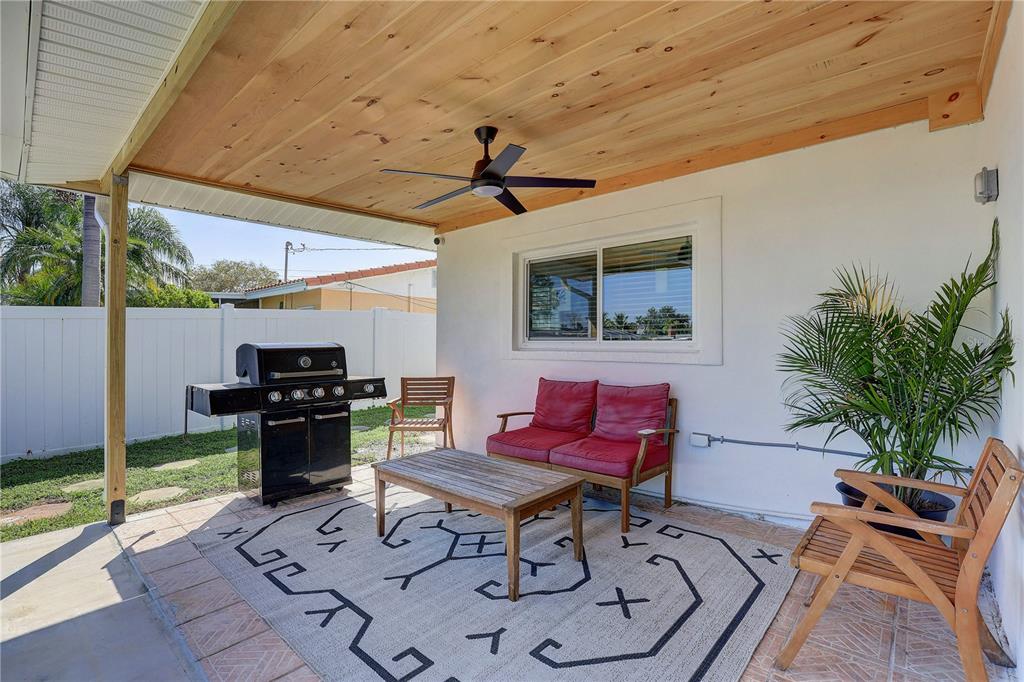 A covered patio features a wood-paneled ceiling, a ceiling fan, a grill, and outdoor furniture — 265 96TH AVENUE N, ST PETERSBURG, FL