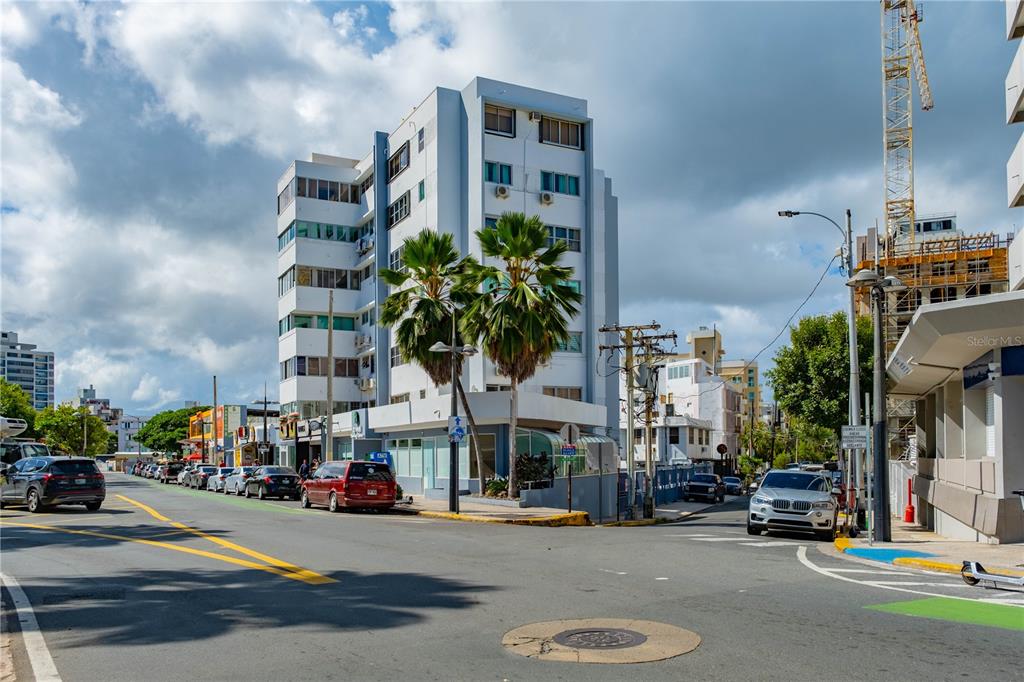 A multi-story apartment building stands on a street corner with palm trees and parked cars — Ashford St. COND. CONDADO CENTER UNIT 1102, SAN JUAN, PR