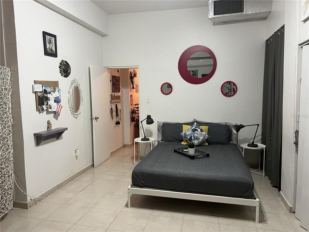 A bedroom features a bed with dark gray bedding, white tile floors, and wall-mounted mirrors — Ashford St. COND. CONDADO CENTER UNIT 1102, SAN JUAN, PR