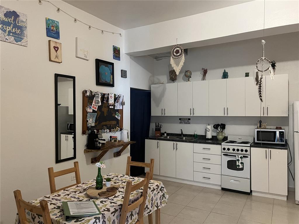 A kitchen and dining area with white cabinets, a patterned tablecloth, and wall decorations — Ashford St. COND. CONDADO CENTER UNIT 1102, SAN JUAN, PR