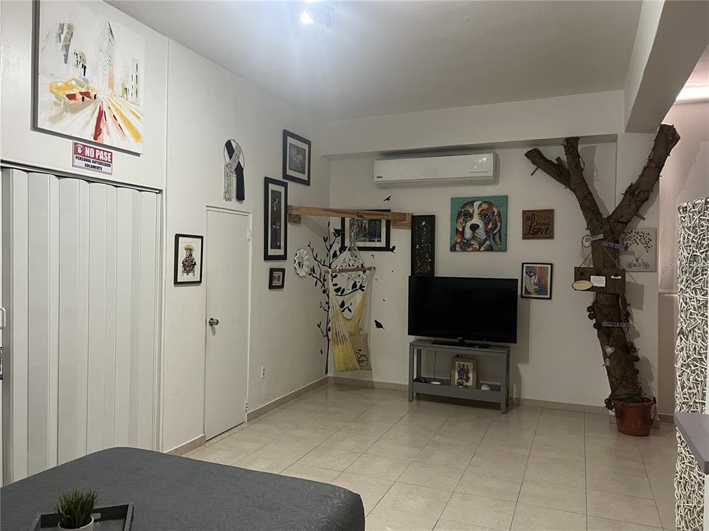 A living room features a television, a decorative tree, a hanging chair, and tiled floors — Ashford St. COND. CONDADO CENTER UNIT 1102, SAN JUAN, PR