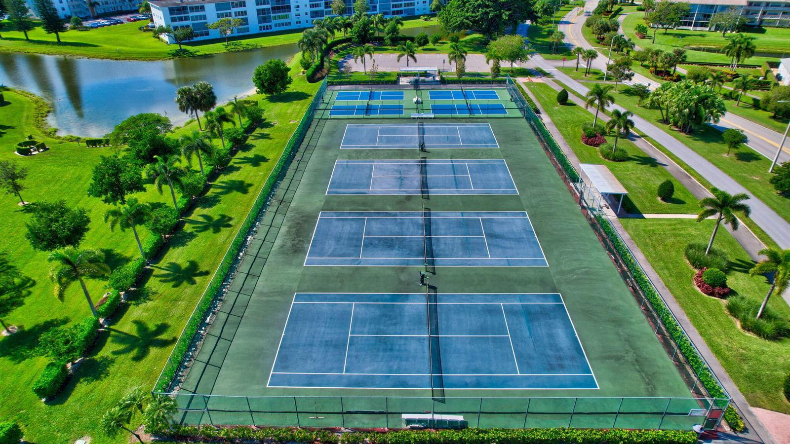 An aerial view of four outdoor tennis courts surrounded by green lawns and palm trees — 3008 Rexford, Boca Raton FL 33434, BOCA RATON, FL
