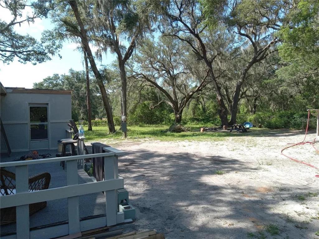 A tan mobile home features a colorful painted walkway and stairs under large oak trees — 16395 SE 117TH AVENUE, WEIRSDALE, FL