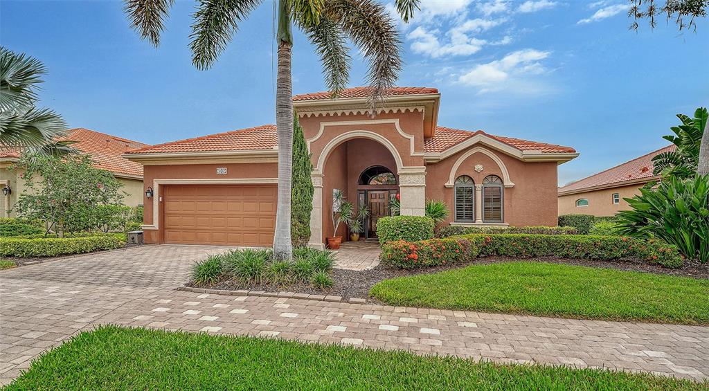 A single-story stucco house with a tile roof, arched entryway, and a paved driveway — 5157 COTE DU RHONE WAY, SARASOTA, FL