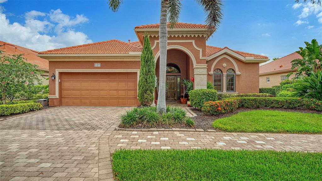 A single-story house with a terracotta tile roof, stucco exterior, and a paved driveway — 5157 COTE DU RHONE WAY, SARASOTA, FL