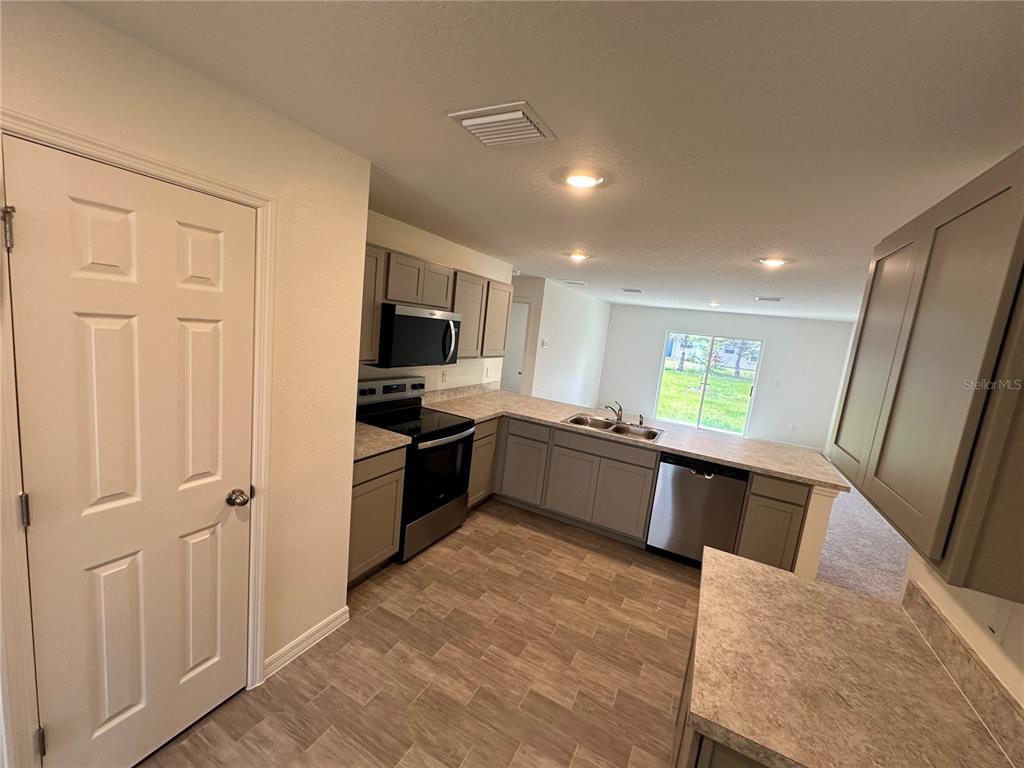 A kitchen features gray cabinets, stainless steel appliances, and a window overlooking a grassy yard — 48 RIPPLING BROOK DRIVE, PALM COAST, FL