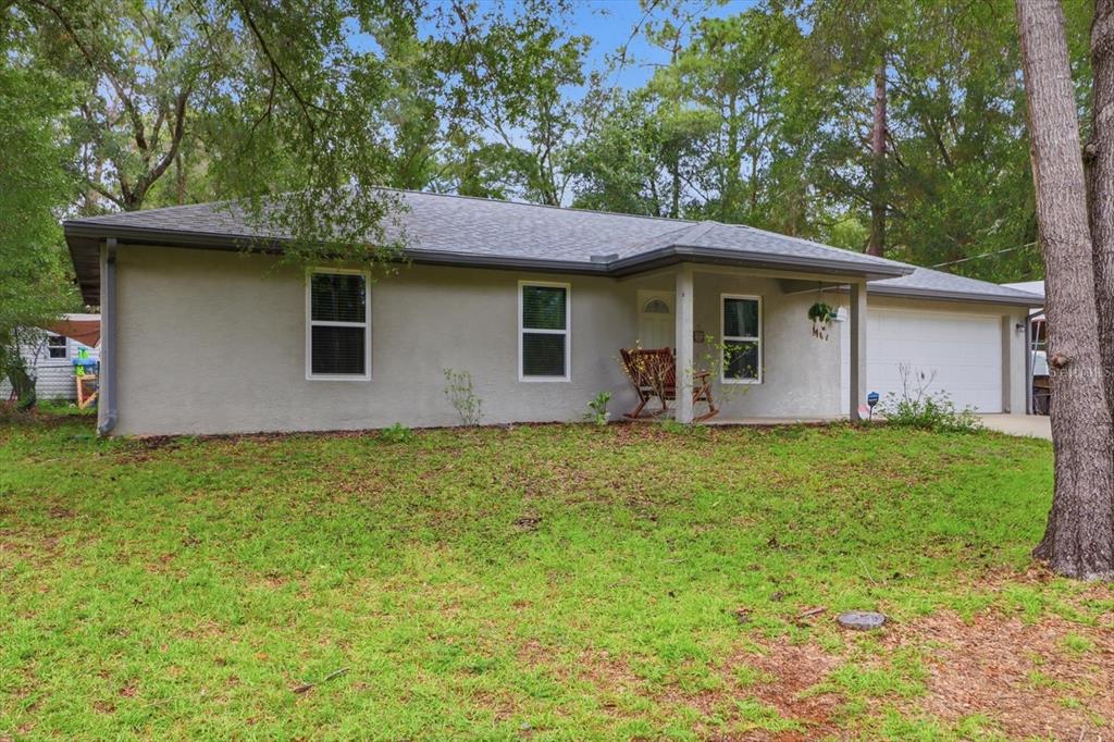 A single-story house with a gray stucco exterior, a shingled roof, and an attached garage — 6461 E MOBILE STREET, INVERNESS, FL