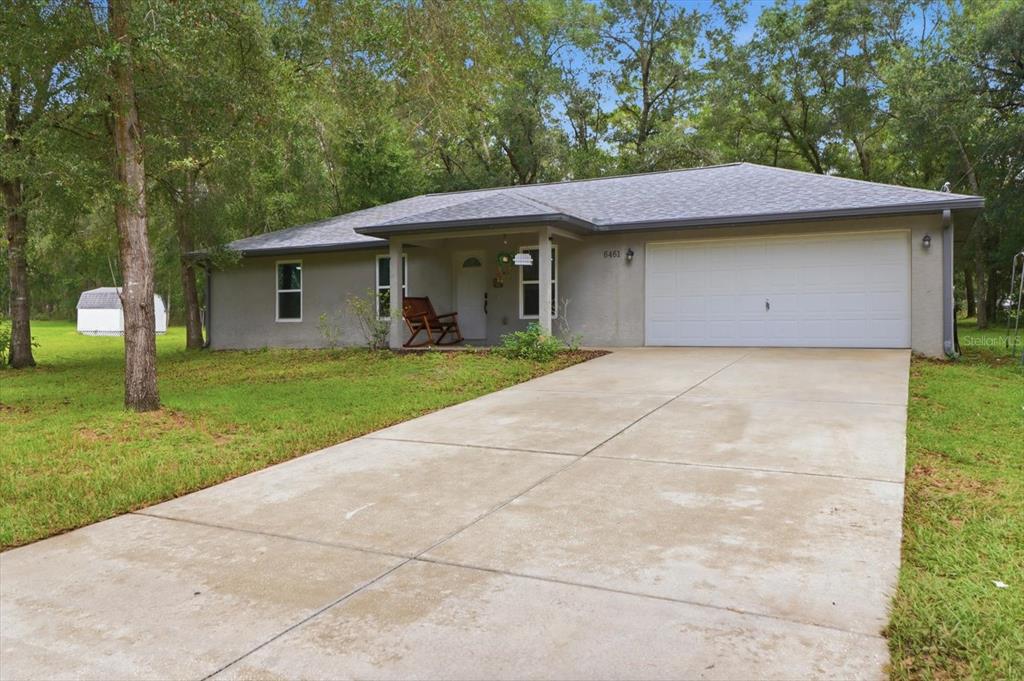A single-story house with a gray stucco exterior, a concrete driveway, and a two-car garage — 6461 E MOBILE STREET, INVERNESS, FL
