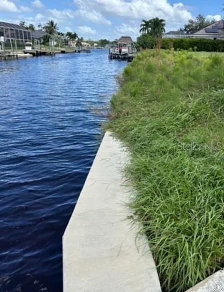 A concrete seawall borders a grassy lawn along a residential canal with boats in view — 2005 SE 20TH LANE, CAPE CORAL, FL