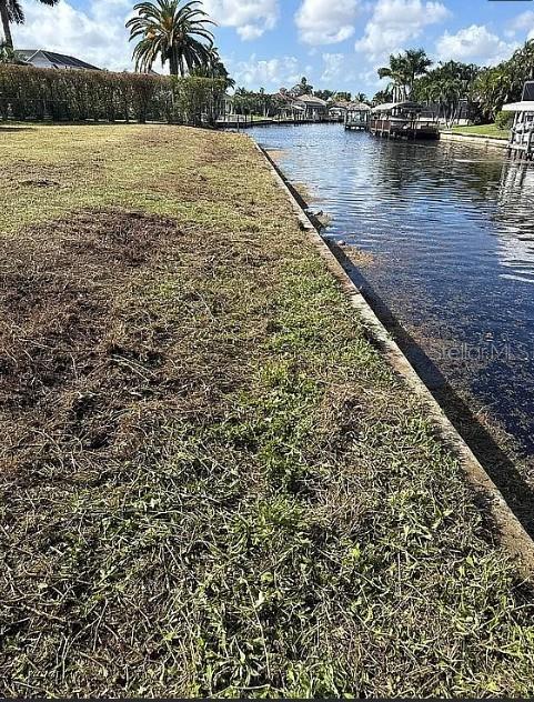 A grassy waterfront lot borders a canal with a concrete seawall and distant houses — 2005 SE 20TH LANE, CAPE CORAL, FL