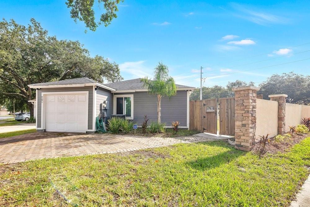 A gray house with a white garage door, brick driveway, and a stone-pillared fence — 701 ASHLEY LANE, ORLANDO, FL