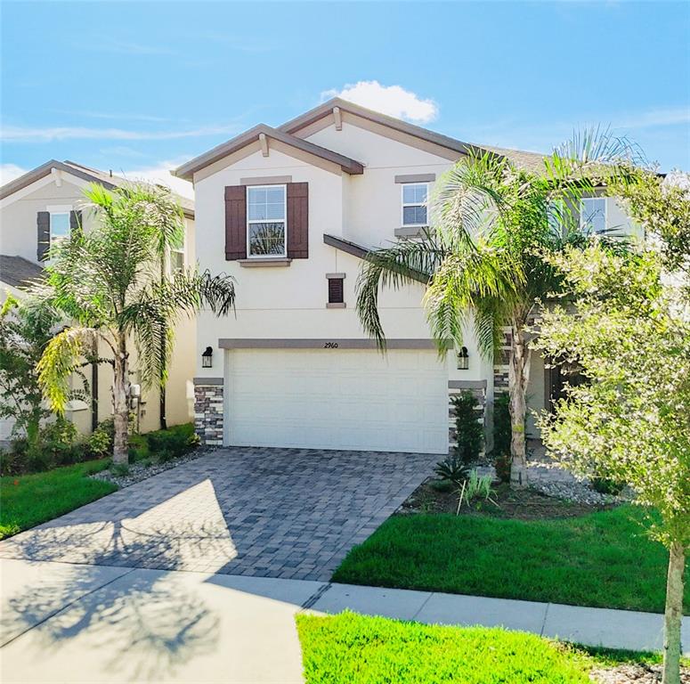 A two-story suburban house features a paved driveway, a two-car garage, and palm trees — 2960 AUTUMN ROCK DRIVE, ZEPHYRHILLS, FL