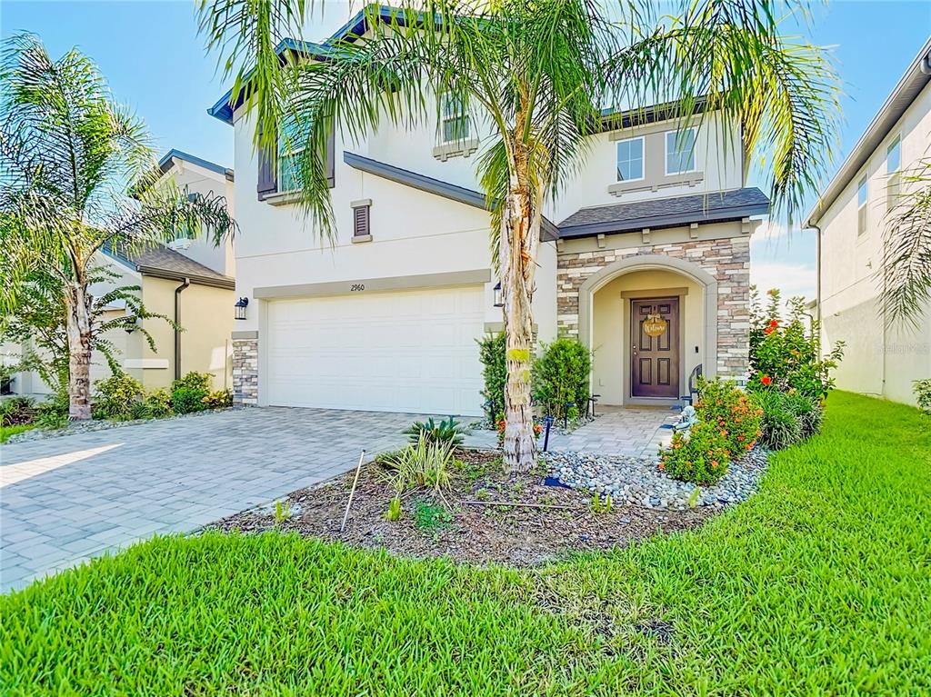 A two-story house with a white stucco facade, stone accents, and a paved driveway — 2960 AUTUMN ROCK DRIVE, ZEPHYRHILLS, FL