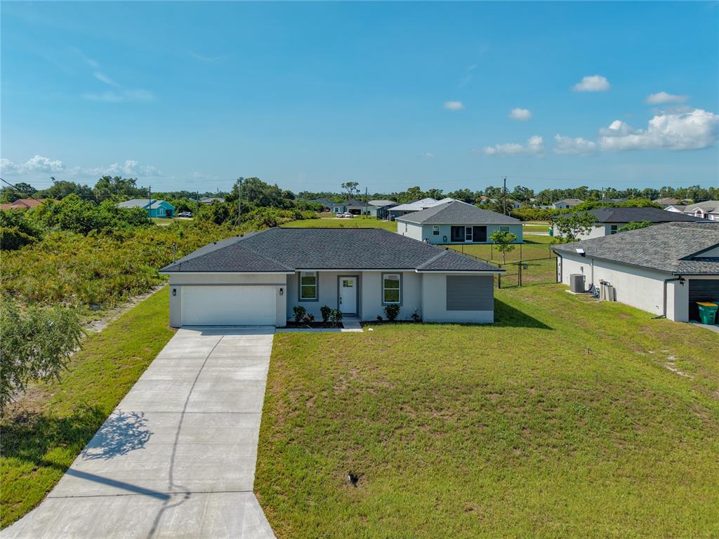 An aerial view of a single-story house with a gray roof and concrete driveway — 12219 BACCHUS ROAD, PORT CHARLOTTE, FL