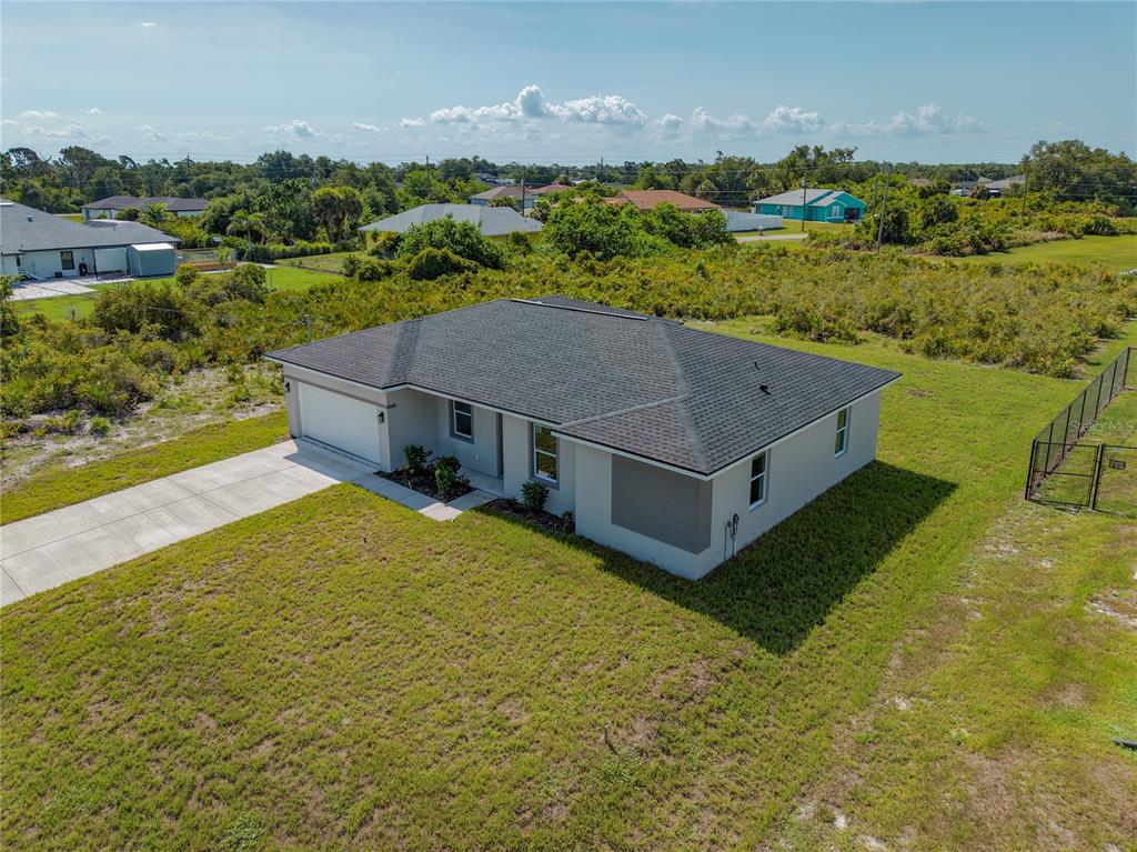 An aerial view of a single-story house with a gray roof and a concrete driveway — 12219 BACCHUS ROAD, PORT CHARLOTTE, FL
