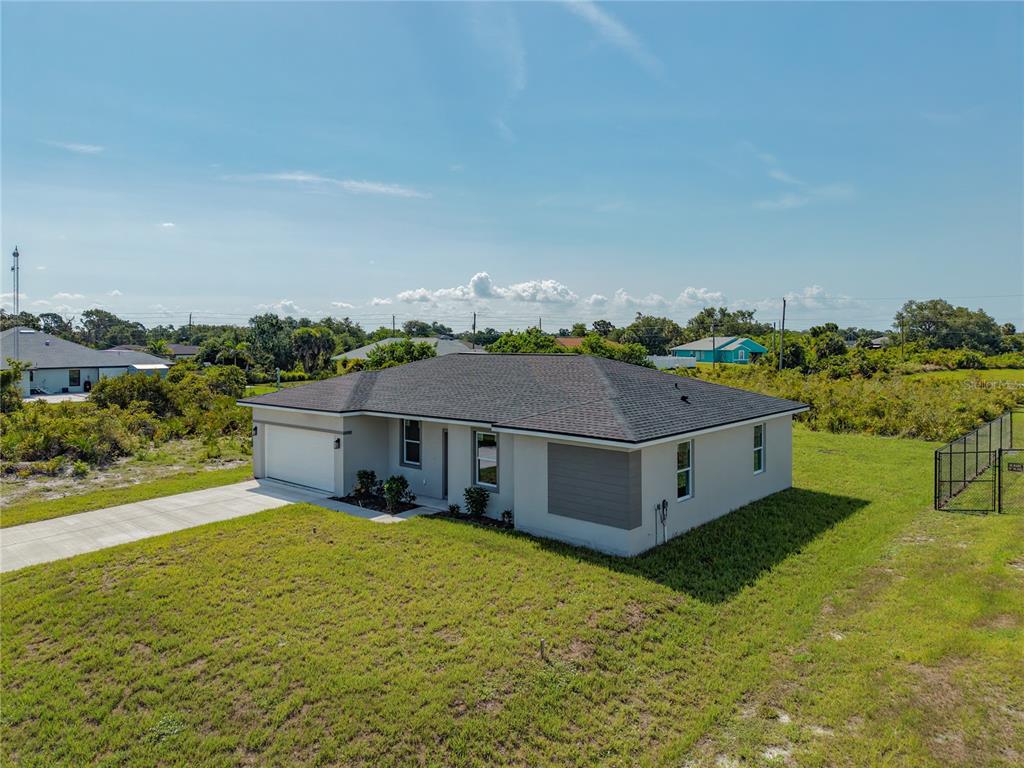 An aerial view of a single-story house with a gray roof and a concrete driveway — 12219 BACCHUS ROAD, PORT CHARLOTTE, FL