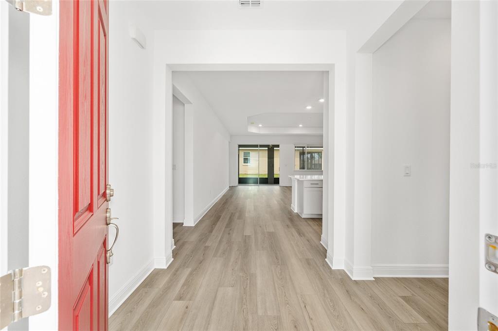A view from an open red front door into a bright, open-concept home interior — 10119 SW 106TH CIRCLE, OCALA, FL