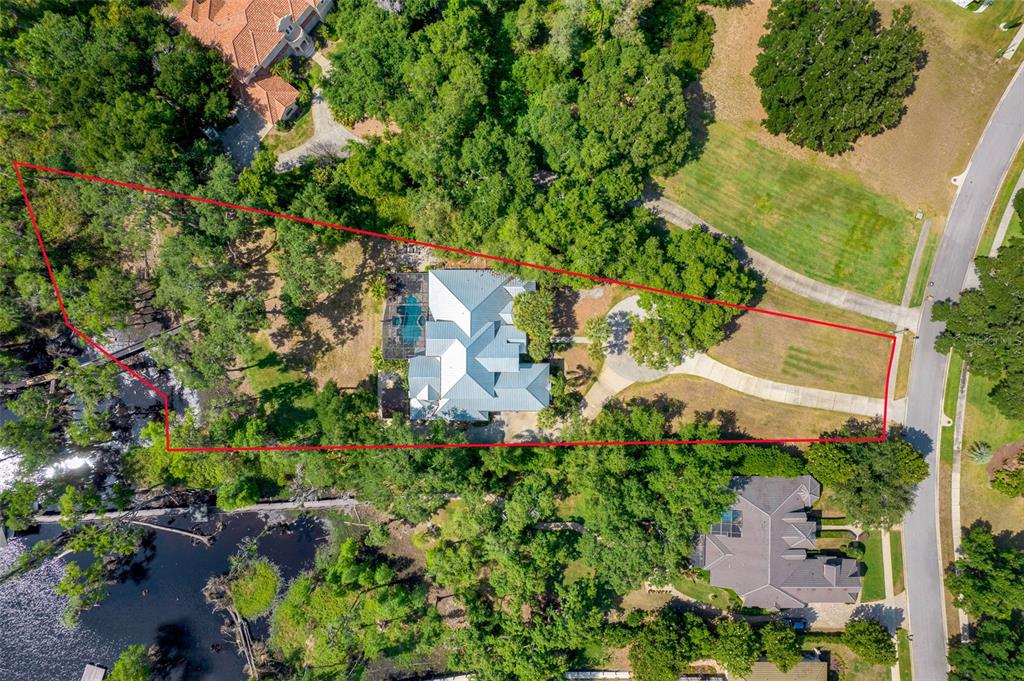 An aerial view shows a house with a pool on a large, wooded lot — 11610 OSPREY POINTE BOULEVARD, CLERMONT, FL