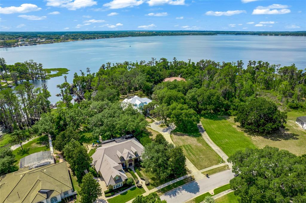 An aerial view shows two houses nestled among trees near a large lake — 11610 OSPREY POINTE BOULEVARD, CLERMONT, FL