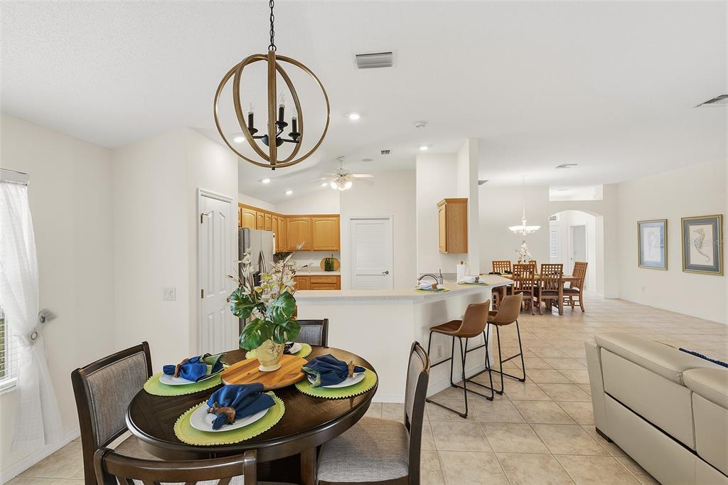 A dining area with a round table and a kitchen with a breakfast bar — 1969 HAGOOD LOOP, THE VILLAGES, FL