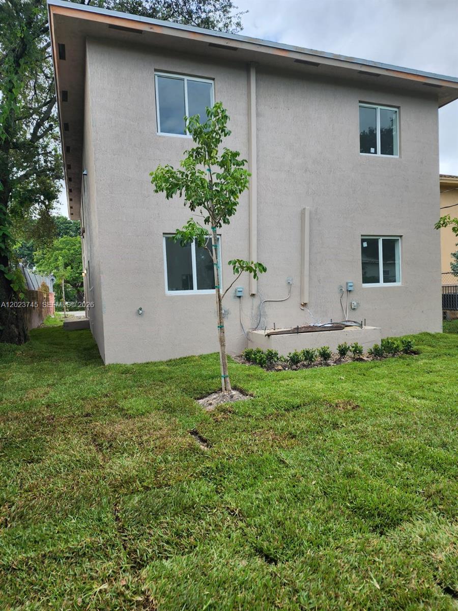 The exterior of a two-story beige stucco building with a small tree in the yard — 2750 NW 58th St # 2752, Miami FL 33142, MIAMI, FL