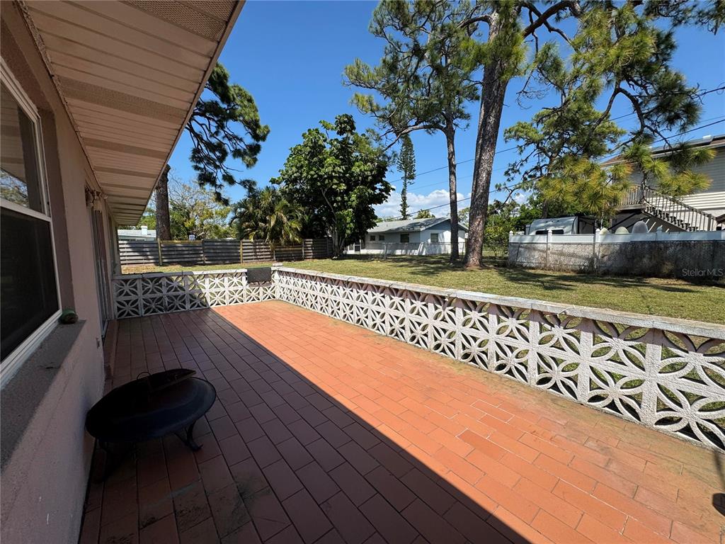 A tiled patio features a decorative concrete block wall overlooking a grassy backyard with trees — 2003 48TH STREET W, BRADENTON, FL
