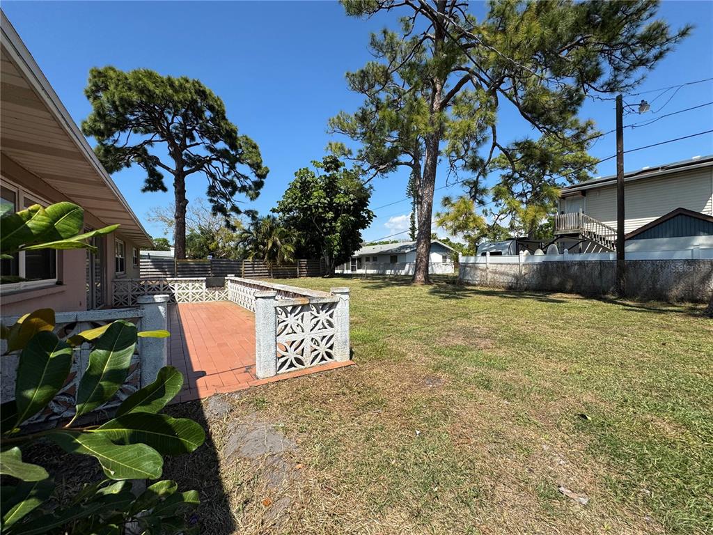 A backyard features a tiled patio with decorative concrete block walls and mature pine trees — 2003 48TH STREET W, BRADENTON, FL