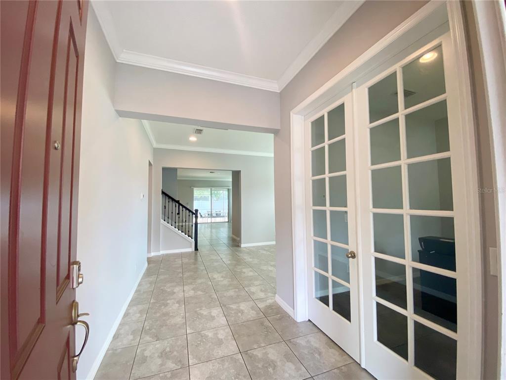 An entryway with tile flooring, a red front door, and white French doors — 1015 GRAND HILLTOP DRIVE, APOPKA, FL