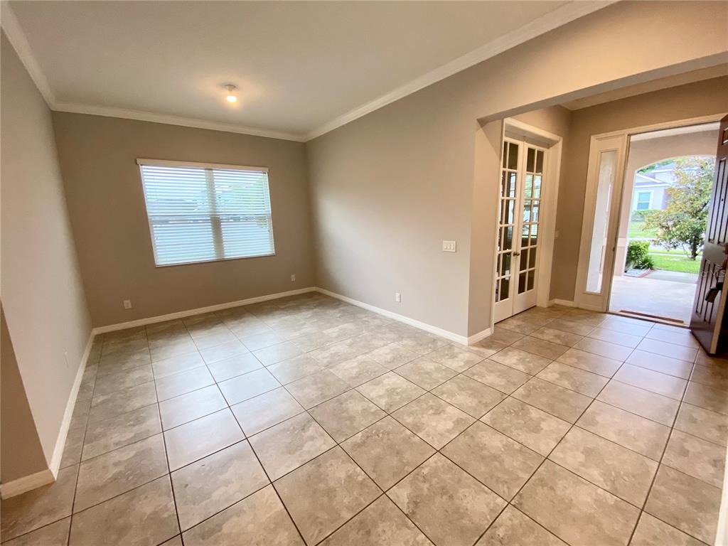 A room with beige walls, tiled flooring, a window with blinds, and a glass-paned door — 1015 GRAND HILLTOP DRIVE, APOPKA, FL