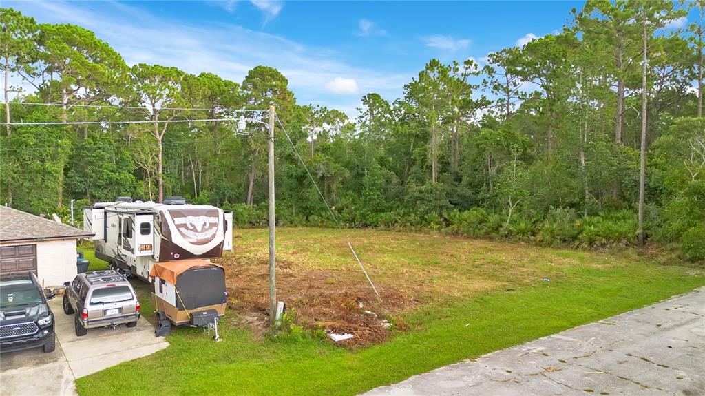 An aerial view shows a vacant grassy lot next to a parked RV and truck — 3198 SNOW DRIVE, DELTONA, FL