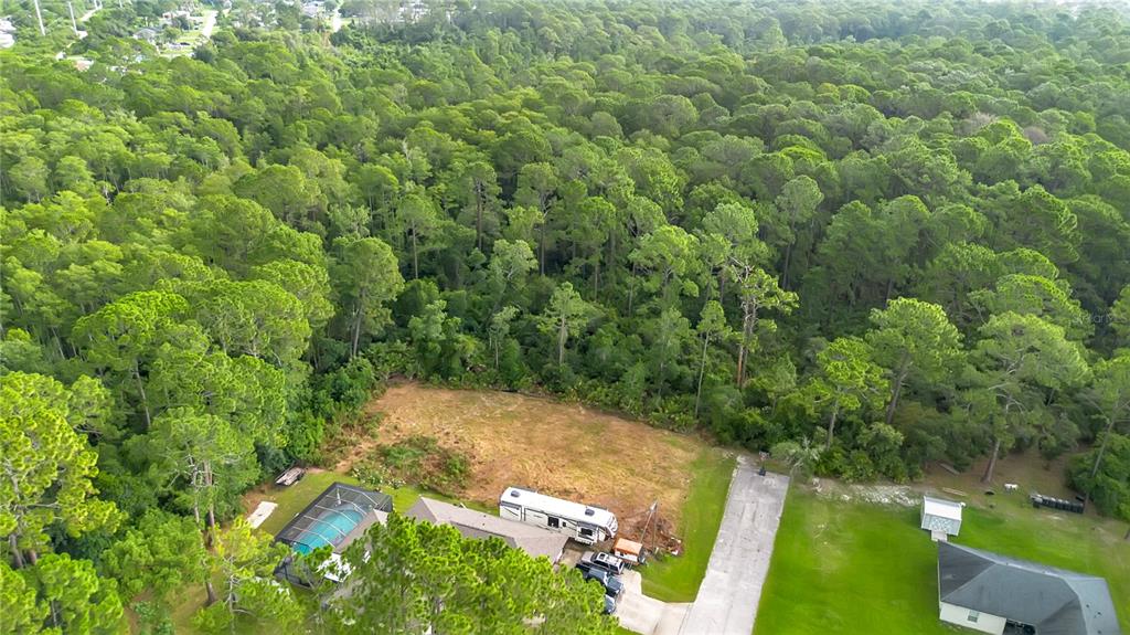 An aerial view shows a residential lot with a house, pool, RV, and surrounding forest — 3198 SNOW DRIVE, DELTONA, FL