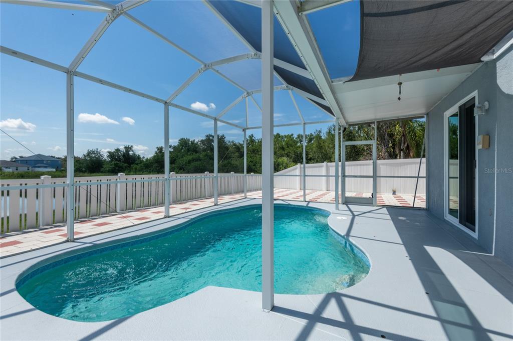 A screened-in pool patio features a kidney-shaped pool, concrete decking, and a white fence — 10907 GOLDEN SILENCE DRIVE, RIVERVIEW, FL