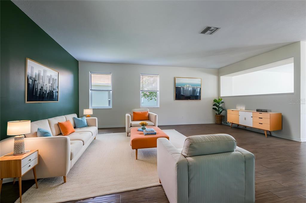 A living room features a green accent wall, light-colored furniture, and dark wood-look flooring — 10907 GOLDEN SILENCE DRIVE, RIVERVIEW, FL