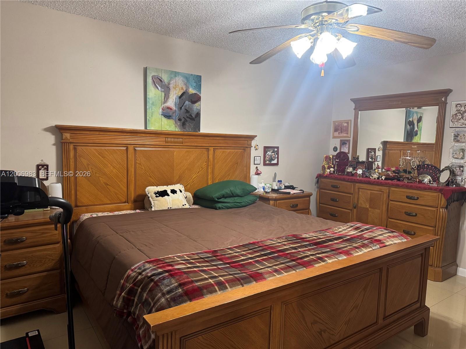 A bedroom features a large wooden bed frame, matching dresser with mirror, and ceiling fan — 471 NE 210TH CIRCLE TER # 103, Miami FL 33179, MIAMI, FL