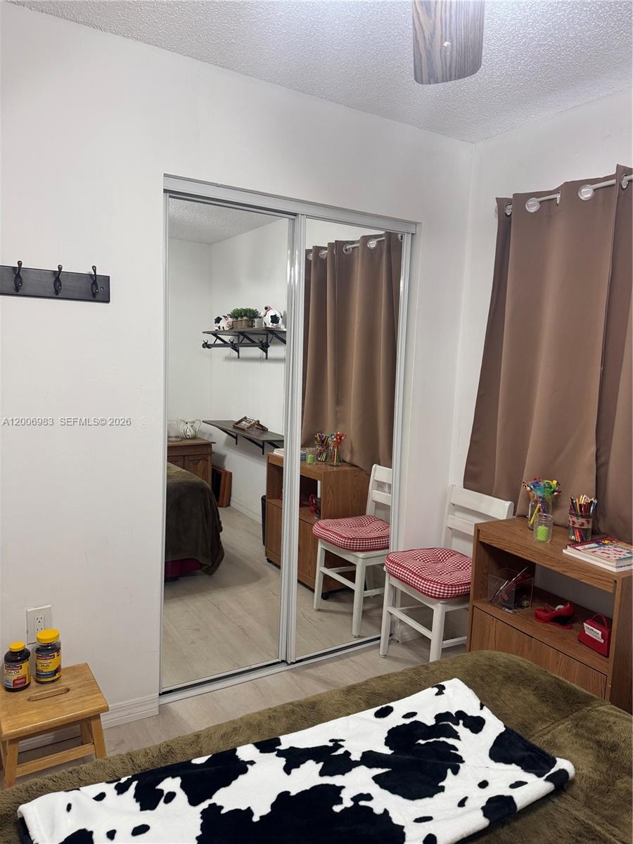 A bedroom features a mirrored closet, a wooden desk, and a cow-print blanket — 471 NE 210TH CIRCLE TER # 103, Miami FL 33179, MIAMI, FL