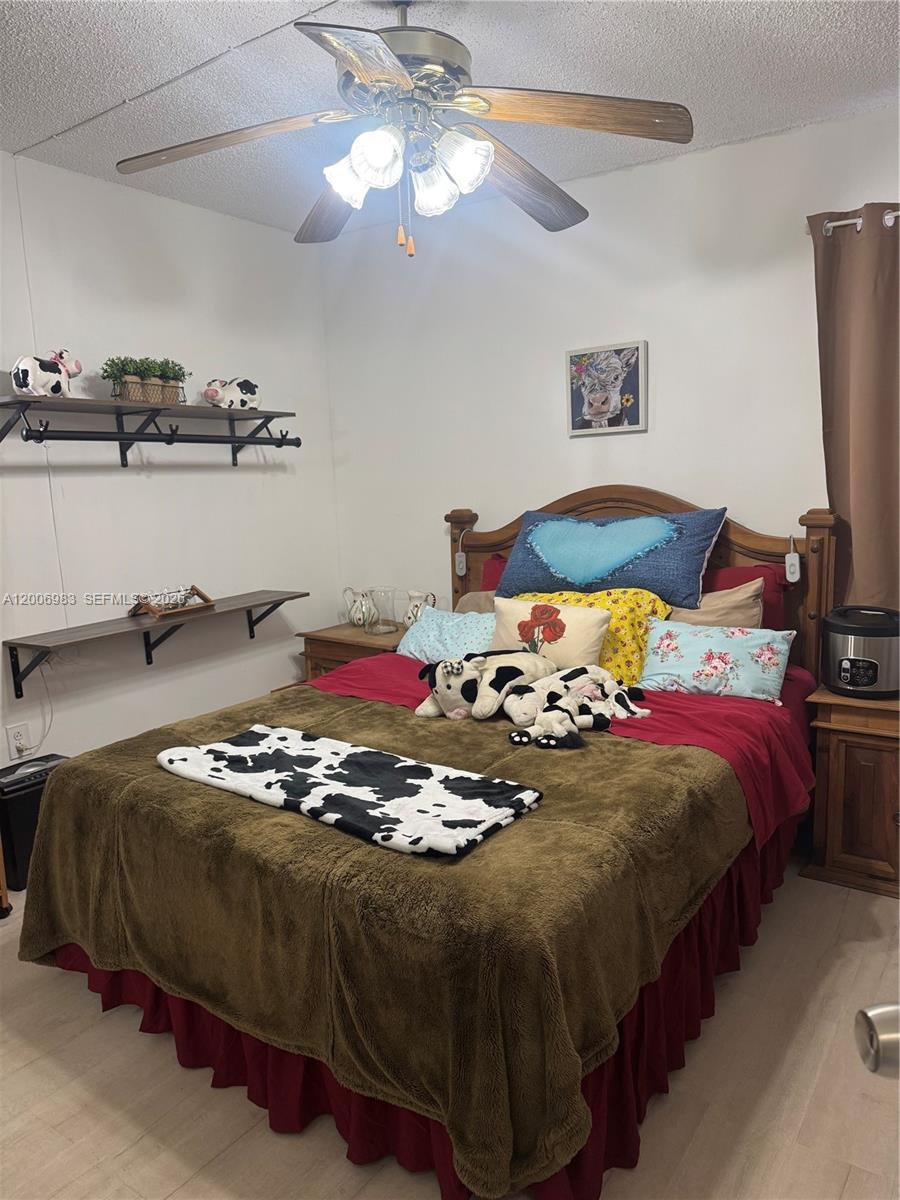 A bedroom features a wooden bed frame, cow-themed decor, and a ceiling fan — 471 NE 210TH CIRCLE TER # 103, Miami FL 33179, MIAMI, FL