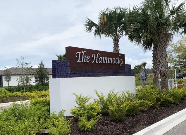 A sign for The Hammocks stands in front of palm trees and a residential building — 16863 FIESTA DRIVE, PORT CHARLOTTE, FL