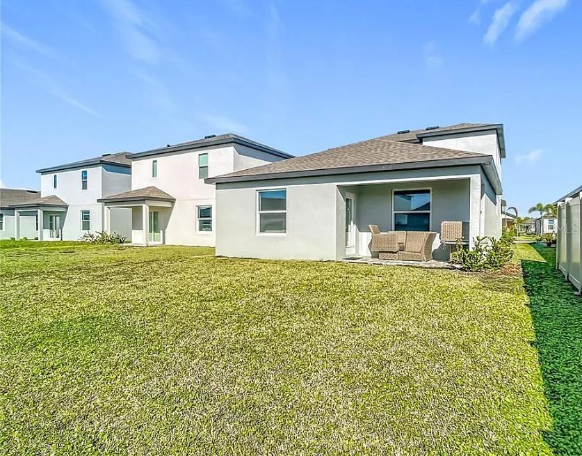 The exterior view shows the back of a light-colored house with a grassy yard — 16863 FIESTA DRIVE, PORT CHARLOTTE, FL