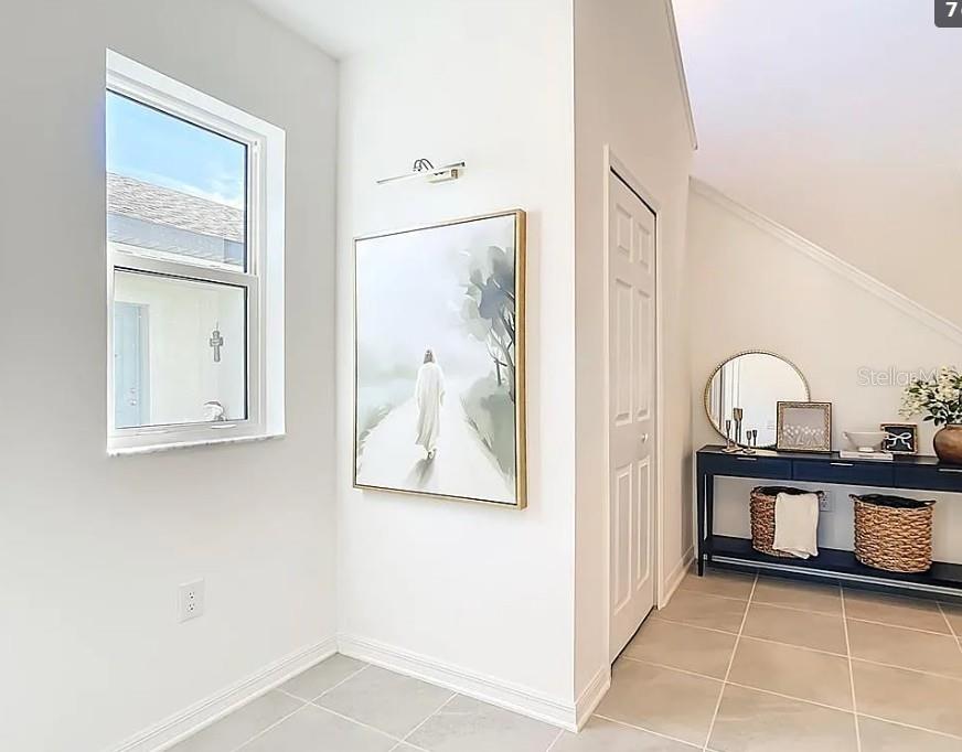 A bright entryway features a framed painting, a console table with baskets, and tiled flooring — 16863 FIESTA DRIVE, PORT CHARLOTTE, FL