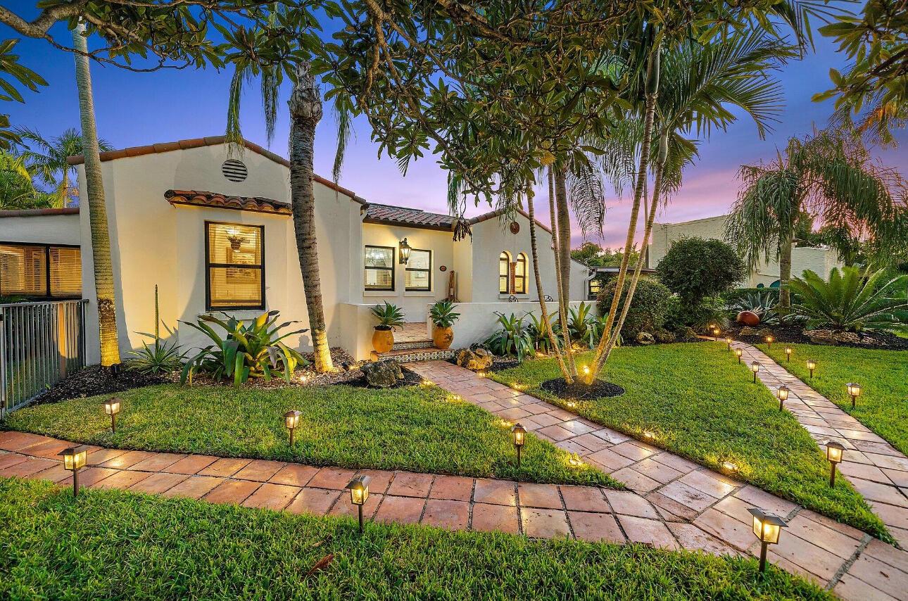 A Spanish-style house with a tiled walkway, palm trees, and landscape lighting at dusk — 400 33rd Street, West Palm Beach FL 33407, WEST PALM BEACH, FL