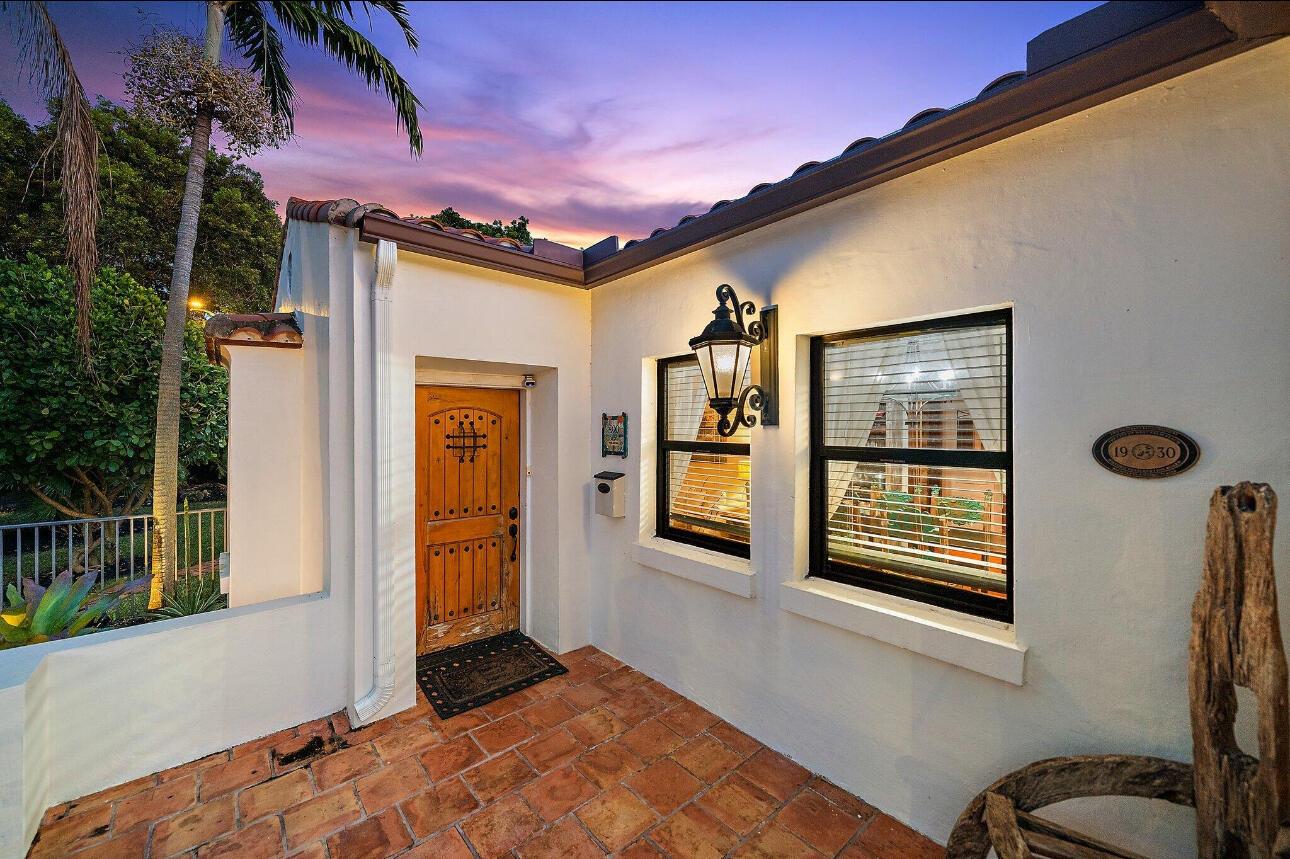 A stucco house exterior features a wooden door, terracotta tile patio, and a vintage plaque — 400 33rd Street, West Palm Beach FL 33407, WEST PALM BEACH, FL